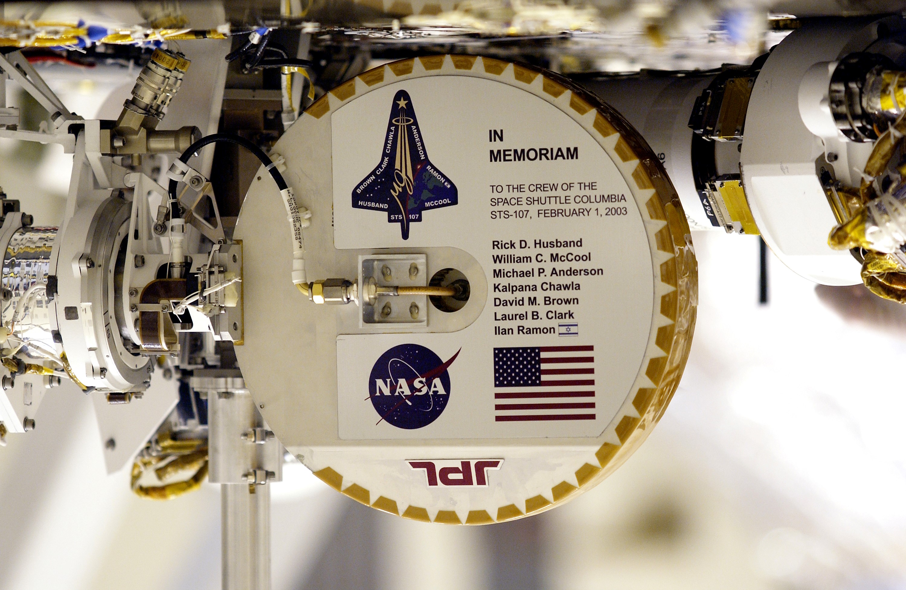 KENNEDY SPACE CENTER, FLA. --Shown upside down to read the names, this plaque commemorating the STS-107 Space Shuttle Columbia crew now looks over the Mars landscape after the successful landing and deployment of the Mars Exploration Rover “Spirit” Jan. 4 onto the red planet.  The plaque, mounted on the high-gain antenna, is shown while the rover underwent final checkout March 28, 2003, in the Payload Hazardous Servicing Facility at KSC. — Mars image from the NASA archive